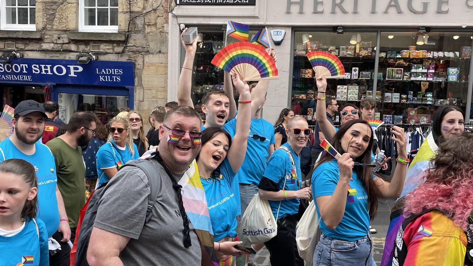 a group of people in a street with rainbow flags